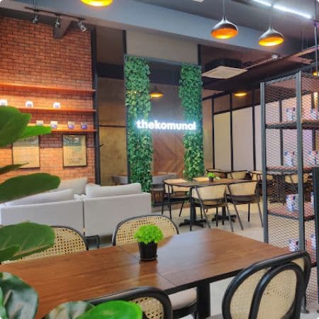 Inside The Komunal Bukit Rimau: rattan chairs, sofa seating, green walls and pendant lights