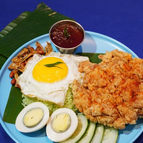 Nasi lemak pandan on a banana leaf with a fried egg, crispy chicken and sambal